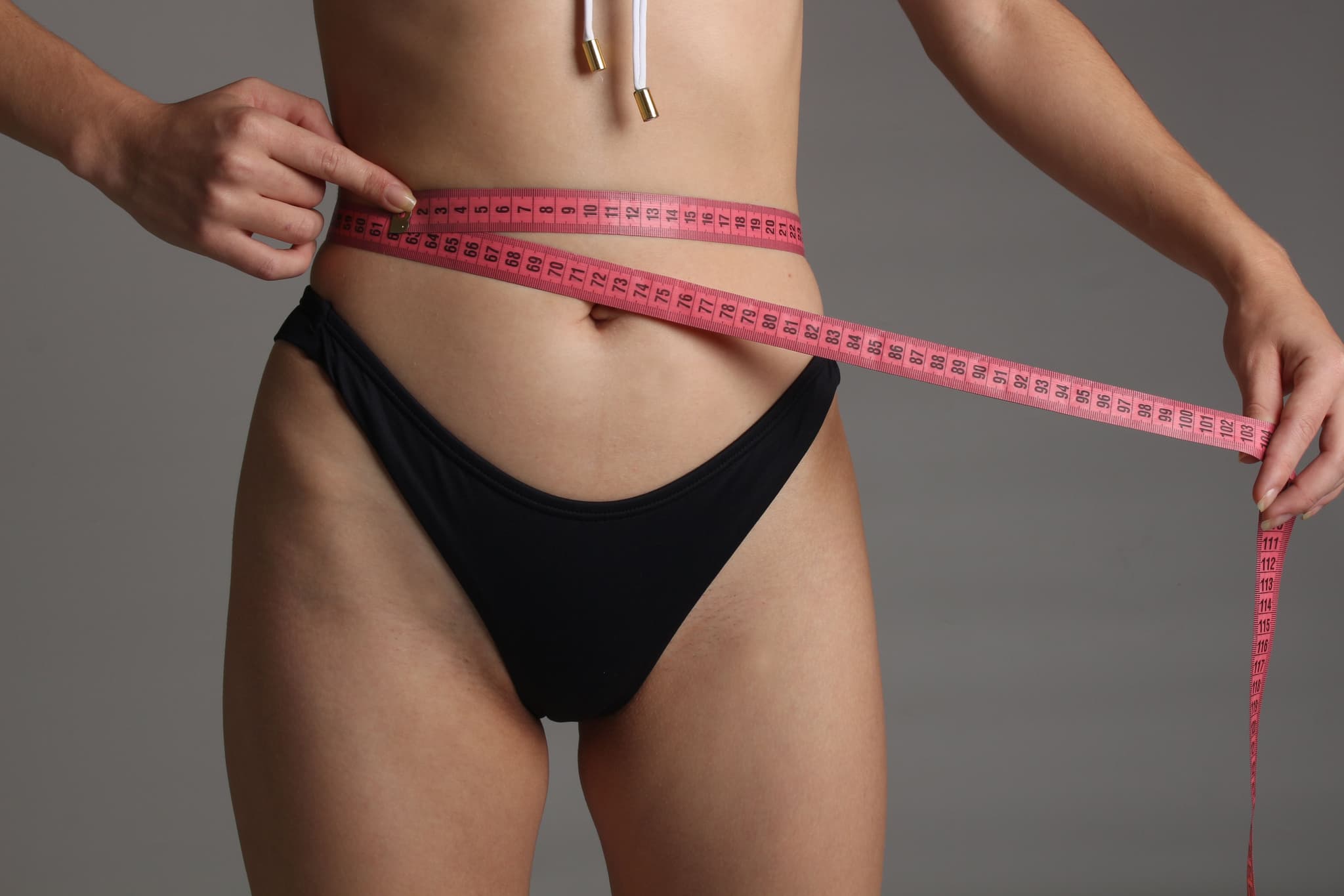 Mujer midiendo su cintura para evaluar una lipoescultura o liposucción.